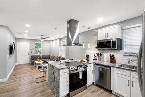 A modern kitchen with white cabinets, a built-in oven, a microwave, and a dishwasher. - Remodeled 3BR, 6 Min to Busch Gardens | Fenced Yard, Monthly Stays Welcome (Tampa)