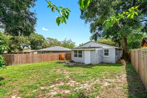 Un jardin à l’arrière d’une maison, avec une clôture en bois, un garage séparé et une pelouse.
