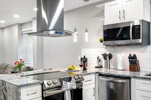 Une cuisine moderne équipée d’appareils électroménagers en acier inoxydable, d’un four encastré, d’un four à micro-ondes et d’un lave-vaisselle.