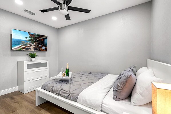 A bedroom with a bed, a dresser, a TV, and a ceiling fan. - Remodeled 3BR, 6 Min to Busch Gardens | Fenced Yard, Monthly Stays Welcome (Tampa)