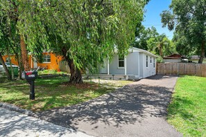 A residential area with a mailbox, a pathway, and a small house with a fenced yard. - Remodeled 3BR, 6 Min to Busch Gardens | Fenced Yard, Monthly Stays Welcome (Tampa)