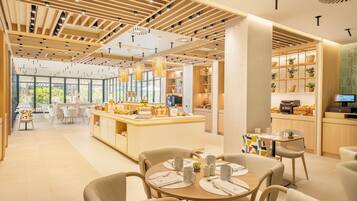 A modern hotel lobby with a central island, seating areas, and a kitchen visible in the background.