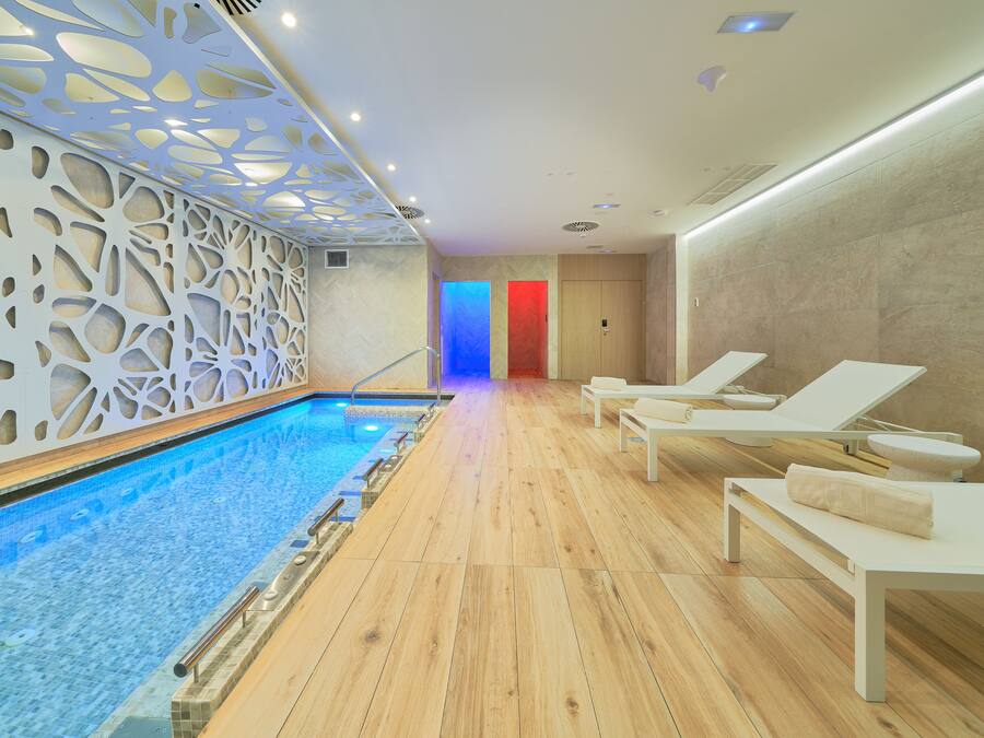 Ein moderner, überdachter Poolbereich mit Holzboden, Liegestühlen und einer dekorativen Decke.