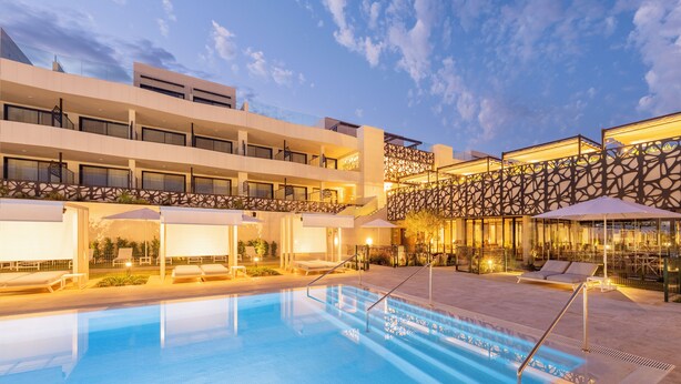Un hotel con piscina, mobiliario exterior y un diseño arquitectónico moderno.