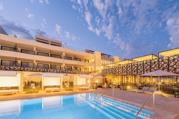 Un hotel con piscina, mobiliario exterior y un diseño arquitectónico moderno.