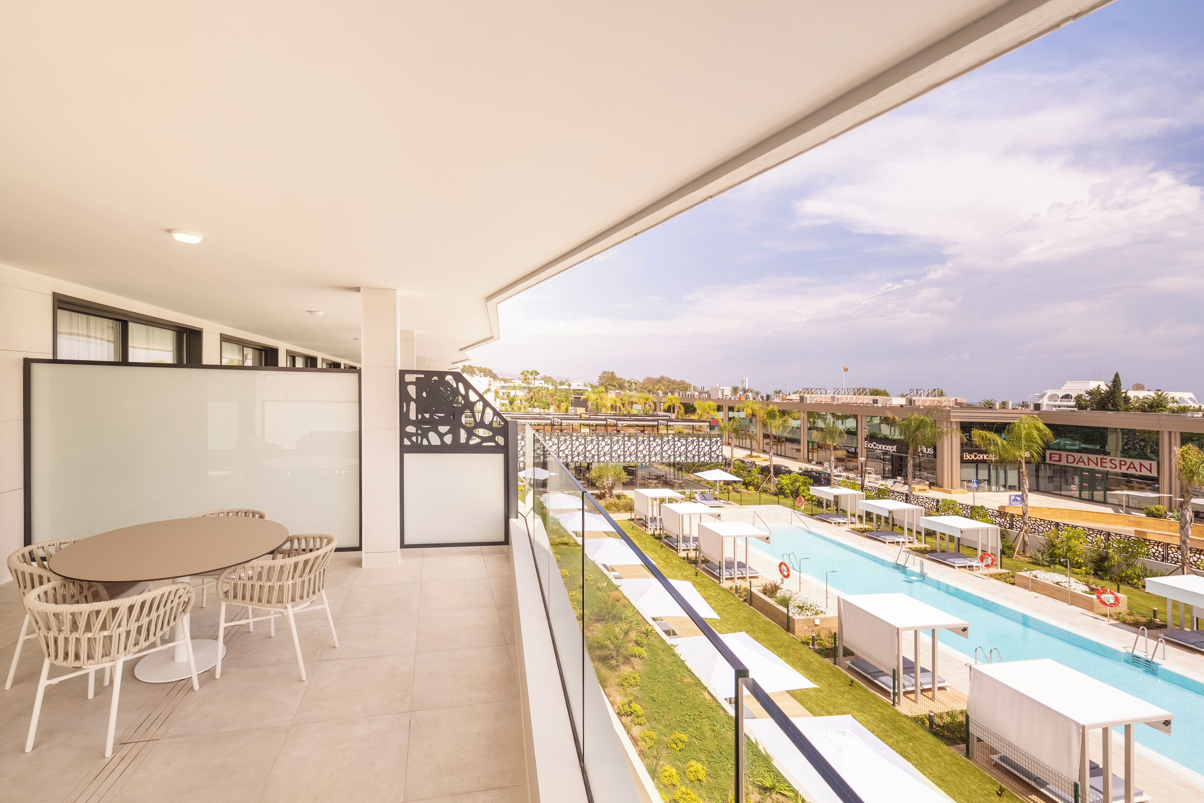 A balcony with a pool, outdoor seating, and a view of the cityscape.