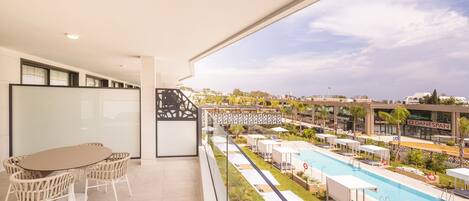 A balcony with a pool, outdoor seating, and a view of the cityscape.