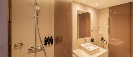A modern bathroom with a glass-enclosed shower, a white sink, and a large mirror.