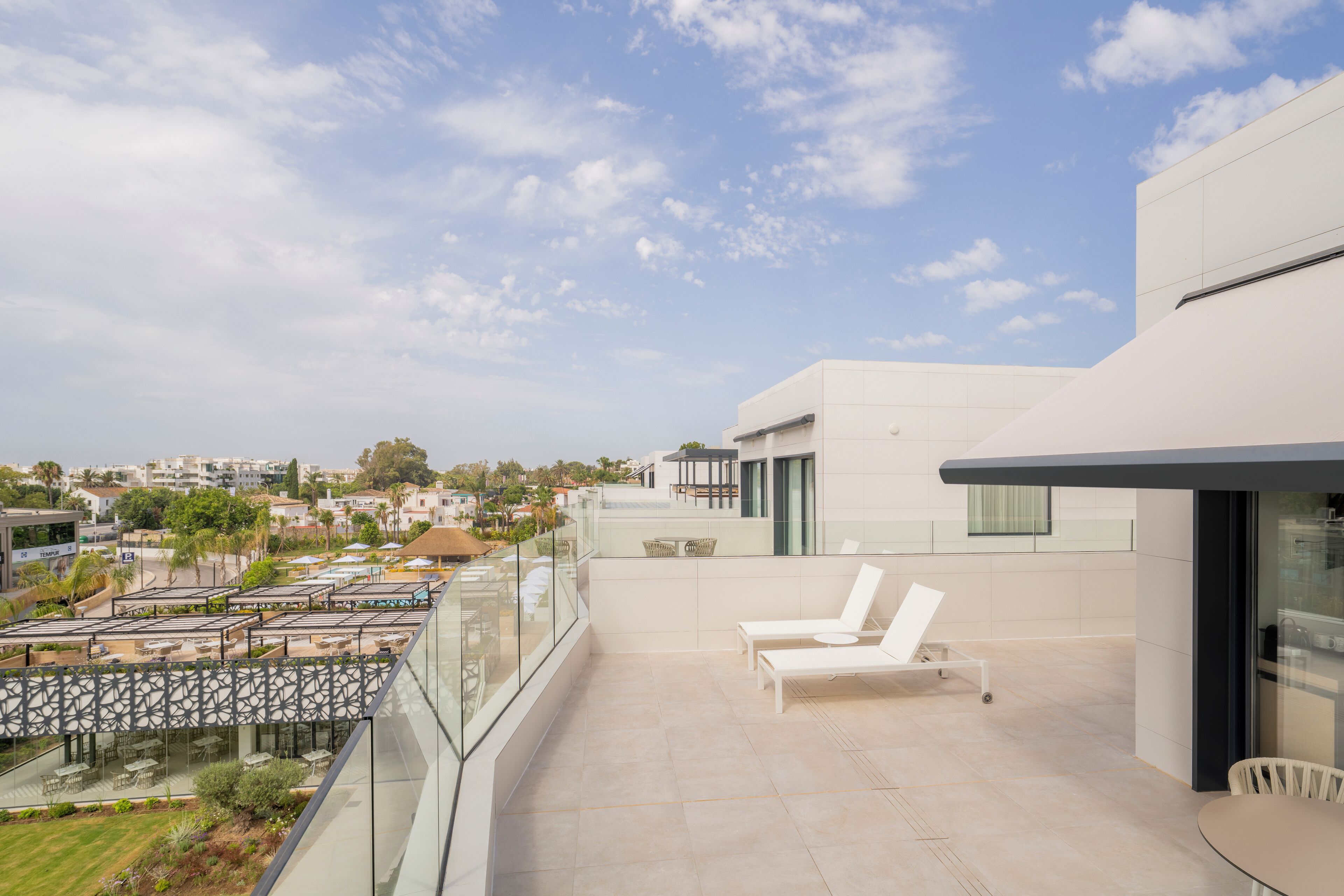 Une terrasse extérieure moderne avec une piscine, des chaises longues et une vue sur la ville.