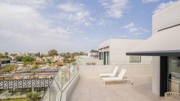 Eine moderne Außenterrasse mit Pool, Liegestühlen und Blick auf die Stadt.