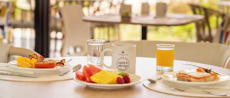 Un desayuno con un plato de comida, una taza y un vaso de zumo de naranja.