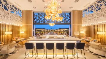 Un intérieur moderne avec un bar central, des espaces aménagés pour s’asseoir et un éclairage décoratif.