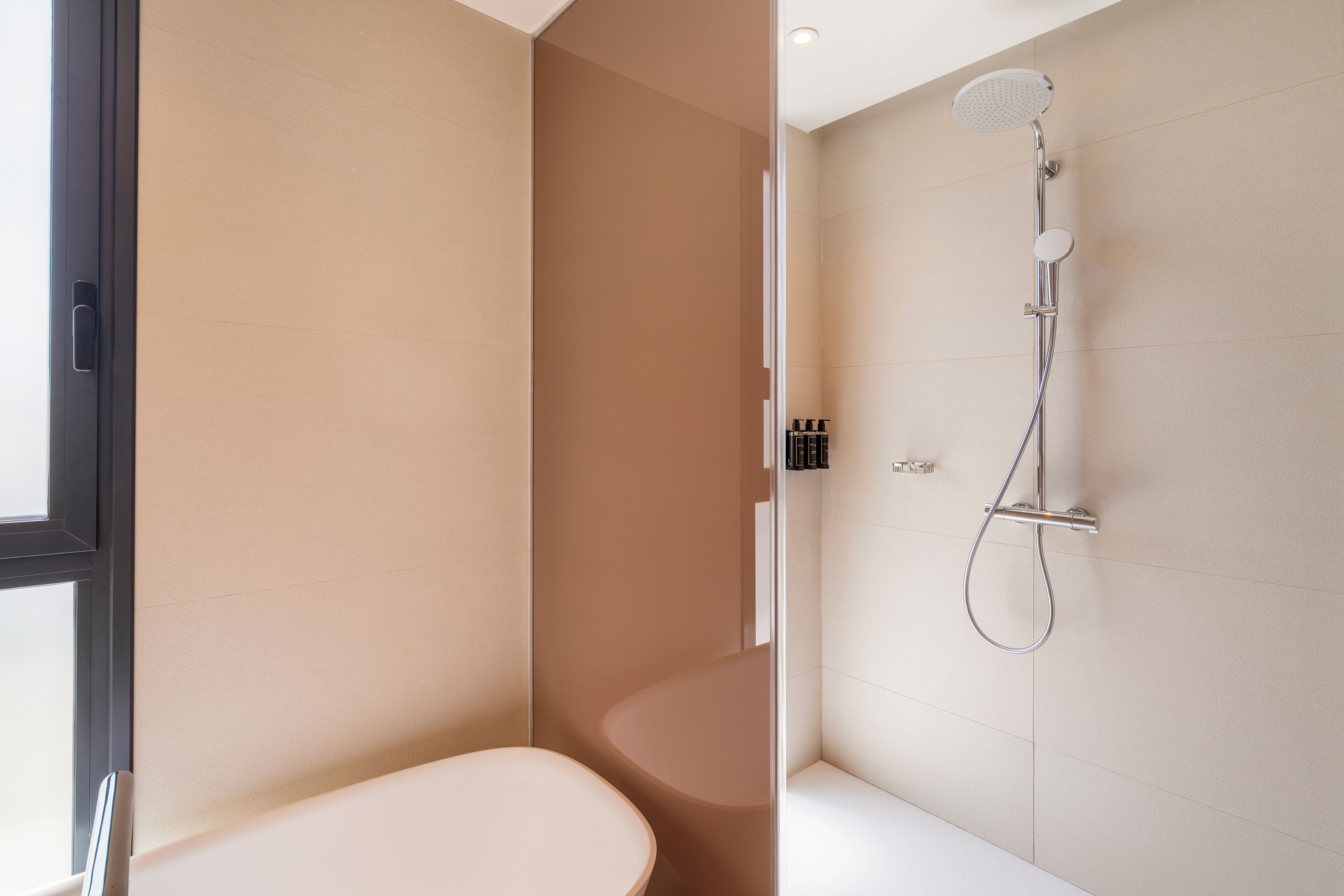 Une salle de bain moderne équipée de toilettes, d’une douche avec un pommeau de douche amovible et d’une baignoire.