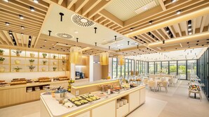 A modern breakfast area with a central counter, shelves with baskets, and a seating area with tables and chairs. - Eurostars Ocean Marbella (Marbella)