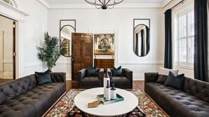 A spacious living room with two dark leather sofas, a round coffee table, and a large mirror on the wall.