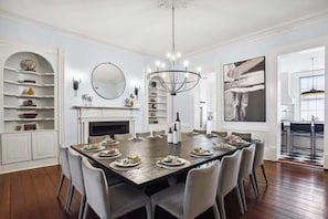 A dining room with a large table set for a meal, a fireplace, and a chandelier.