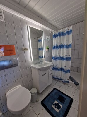 Une salle de bain comprenant des toilettes, un lavabo et un espace douche.