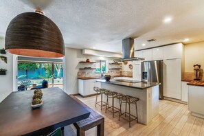 A modern kitchen with a large island, stainless steel appliances, and a pendant light.