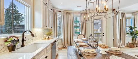 A modern kitchen with a long island, pendant lighting, and a view of the city.