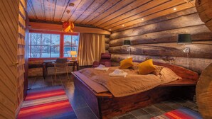 A log cabin bedroom with a wooden bed, a window with curtains, a chair, and a table. - Utsjoki Arctic Resort (Utsjoki)