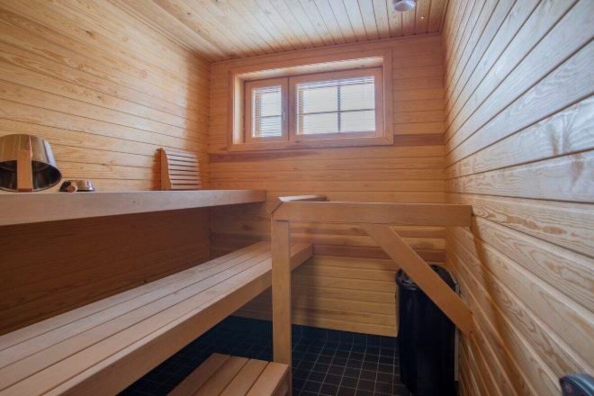 A wooden cabin interior with a sauna, a window, and a bench.