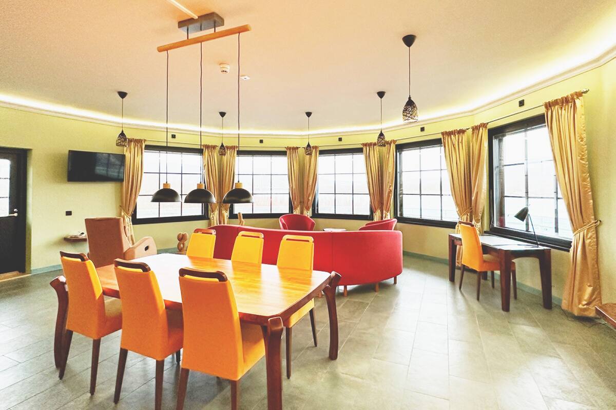 A dining area with a large table and chairs, a sofa, and a TV mounted on the wall.