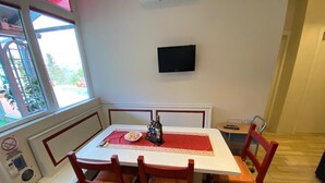 A dining area with a white table, red chairs, a red table runner, and a flat-screen TV mounted on the wall. - NiGiNo house sleeps 6, private pool and garden (Donnini)