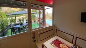 A room with a view of an outdoor patio, a table with a red tablecloth, and a bed with a white headboard. - NiGiNo house sleeps 6, private pool and garden (Donnini)