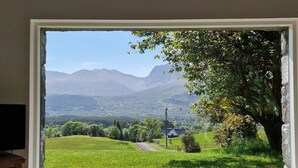 A window with a view of a green field, a tree, and distant mountains. - The Barn in Banavie near Fort William (Fort William)
