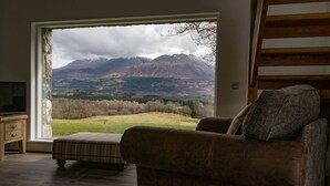 A room with a large window offering a view of mountains and a grassy landscape. - The Barn in Banavie near Fort William (Fort William)
