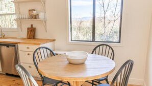 A dining area with a round wooden table, four chairs, and a large window with a view of trees and mountains. - Cozy cottage close to downtown Hayesville (Hayesville)