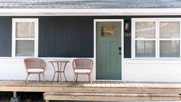 A house with a green door, two wicker chairs, and a small table on a wooden deck. - Cozy cottage close to downtown Hayesville (Hayesville)