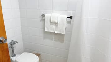 Un baño pequeño y limpio con azulejos blancos, un inodoro, un perchero con dos toallas y una cortina de ducha.