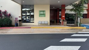 Entrada de hotel con zona de espera cubierta, un letrero del departamento de bomberos y señal de estacionamiento para discapacitados.