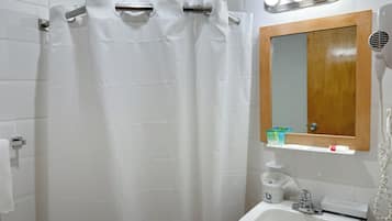 A bathroom with a shower curtain, a sink, a mirror, and a hairdryer.