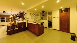 A reception area with a wooden reception desk, potted plants, a fruit bowl, and a ceiling fan. - Antares Dhangethi (Dhangethi)