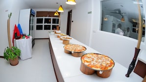 A long buffet table with multiple pizza pans lined up. - Antares Dhangethi (Dhangethi)