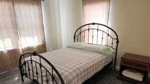 Un llit individual amb estructura metàl·lica, un edredó estampat i una petita taula de nit amb un coixí.