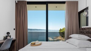 Une chambre d’hôtel avec un lit, un bureau et une vue sur la mer.
