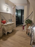 A hallway with a white ornate dresser, a mirror, a red apple, and a potted plant.