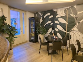 Un comedor con una mesa, sillas, un refrigerador y un mural grande en la pared.
