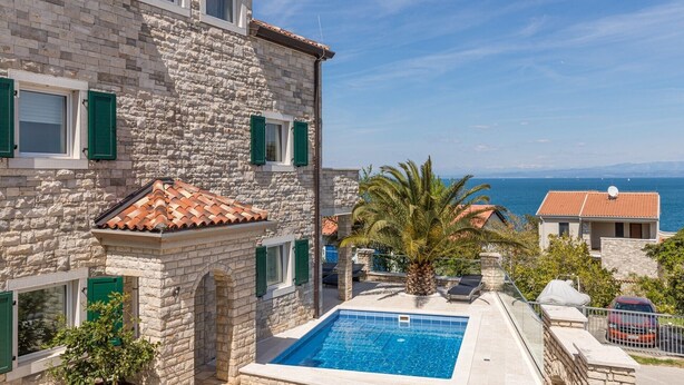 A stone building with a swimming pool, a view of the sea, and a red car parked nearby. - Beautiful Villa Milena with swimming pool (Crveni Vrh)