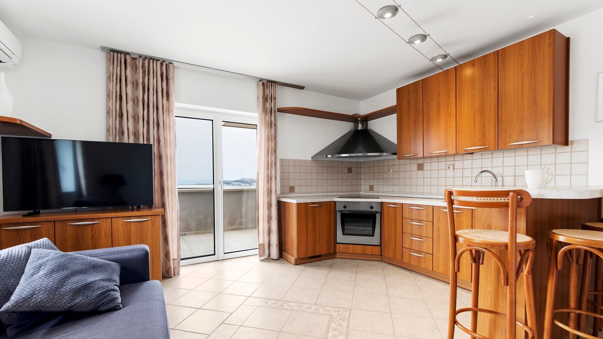A modern kitchen with wooden cabinets, a built-in oven, and a large window.