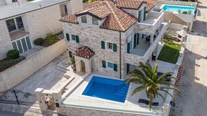 A multi-story building with a swimming pool, stone facade, and green shutters. - Beautiful Villa Milena with swimming pool (Crveni Vrh)