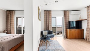 A modern hotel room with a bed, a seating area with a lamp, a television, and an air conditioning unit. - Beautiful Villa Milena with swimming pool (Crveni Vrh)