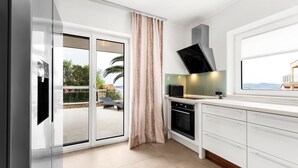 A modern kitchen with a sliding glass door leading to a balcony, a built-in microwave, and a range hood. - Beautiful Villa Milena with swimming pool (Crveni Vrh)