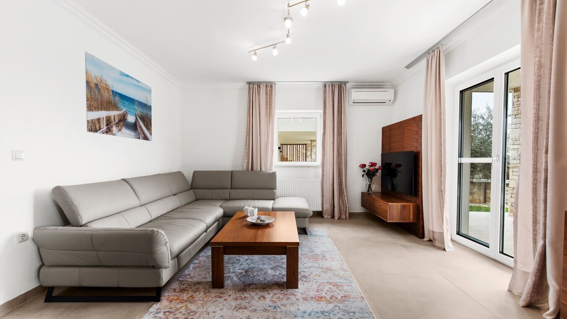 A modern living room with a sectional sofa, a coffee table, and a flat-screen TV.