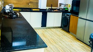 A modern kitchen with a black countertop, stainless steel appliances, and wooden flooring. - Impeccable 2-bed Apartment in Lekki With Snooker (Lekki)