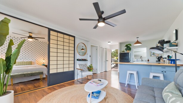 A modern living room with a grey sofa, a round coffee table, and a large potted plant. - Big Island Kailua Village 208 1 Bedroom Condo (Kailua-Kona)