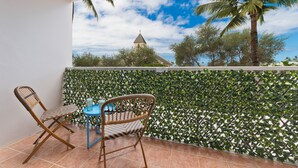 A balcony with a view of a church, a palm tree, and a green leafy wall. - Big Island Kailua Village 208 1 Bedroom Condo (Kailua-Kona)